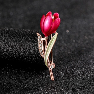 Macro shot of tulip brooch featuring rose red enamel petals and green rhinestone leaves