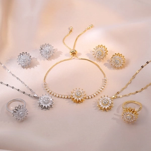 Sunflower jewelry set with emerald zircon and white crystals on pink silk background