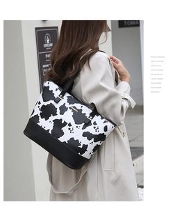 Détail du sac cabas imprimé vache avec ferrures dorées et base en cuir noir sur modèle
