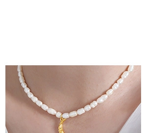 Close-up of Baroque pearl necklace with gold moon pendant on female neck