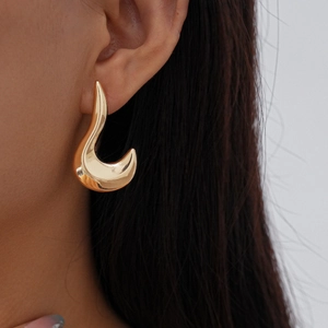 Close-up of golden irregular geometric stud earring with high-polish metallic finish