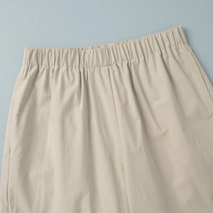 Detail of light beige casual pants showing elastic waistband and fine fabric texture
