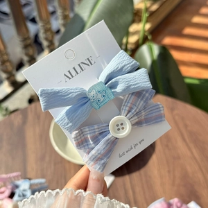 Close-up of blue pleated and plaid bow hair clips with cute bear and button details