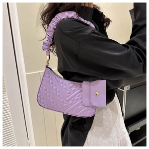 Detail of purple quilted shoulder bag featuring ruffled handle and magnetic clip-on pouch