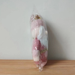 Close-up of pink Christmas Santa plush doll with sequins in protective packaging