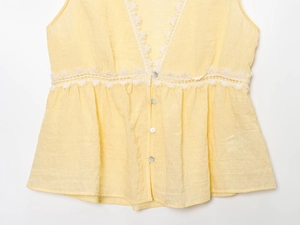 Flat lay of light yellow V-neck lace top with button details and cinched waist