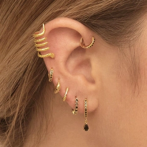 Close-up of a golden snake ear cuff with black zircon studs on a female ear