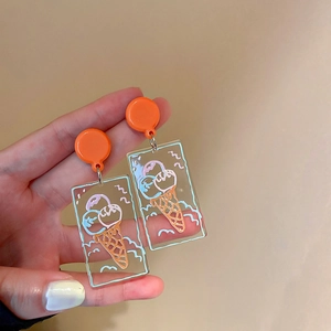 Détail de boucles d'oreilles en acrylique avec motifs de glace et clous orange vifs