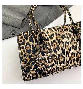 Close-up of leopard print handbag with heart-shaped rivet charm and premium metal hardware