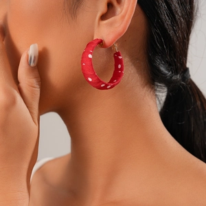 Close-up of model wearing red polka dot fabric hoop earrings with Fu character and lion charms