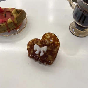 Detail of tortoise shell heart hair claw with white bow on white table setting