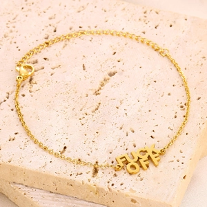 Halskette aus Gold-Edelstahl mit FUCK OFF Buchstaben-Anhänger auf einer Steinfläche