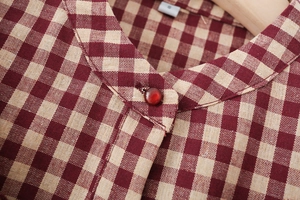 Nahaufnahme einer karierten Bluse mit kleinem Stehkragen und einem runden braunen Knopf