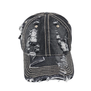 Close-up of vintage black washed denim baseball cap with distressed frayed holes and white stitching