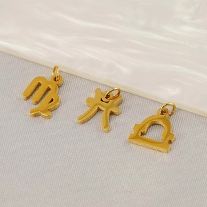 Macro shot of three gold zodiac pendants on textured fabric for DIY necklace making