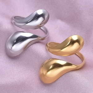 Detail of sleek water drop open rings in gold and silver finish on silk fabric