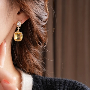 Close-up of 18K gold plated earring with yellow square stone on model's ear