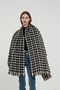Detailed view of oversized houndstooth scarf with soft fringe and thick wool-like texture