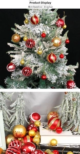 Detail of red and gold Christmas ornaments with snowflake patterns on a snowy pine tree