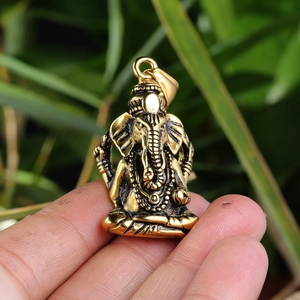 Close-up of a vintage bronze Ganesha pendant with intricate details on a hand