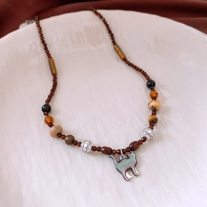 Macro shot of tiger eye beads and shell cat pendant on a vintage style necklace