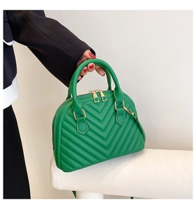 Detail of green shell bag featuring elegant V-quilted stitching and gold metal zipper