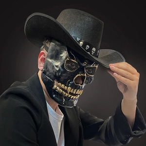 Detail of Halloween skull mask with golden teeth and black cowboy hat accessory