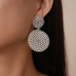 Gros plan de boucles d'oreilles géométriques argentées en maille creuse sur un mannequin