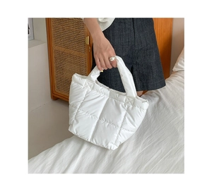 Detail of white quilted puffer handbag with padded handles in a lifestyle home setting