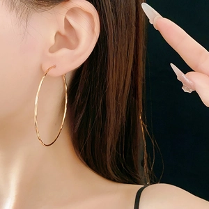Primo piano di un grande orecchino a cerchio d'oro testurizzato indossato da una modella