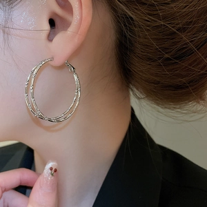 Close-up of textured silver double-hoop earrings featuring a stylish bamboo joint design