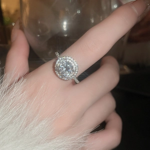 Close-up of a luxury silver halo ring with sparkling zircon stones on a model's hand