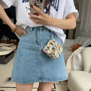 Mini floral fabric storage pouch with button closure hanging on denim skirt belt loop