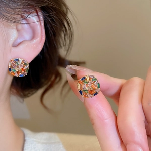 Close-up of gold plated square stud earrings with colorful zirconia stones on ear