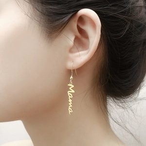 Detail showing hand-written Mama letter earrings in gold finish worn by a model