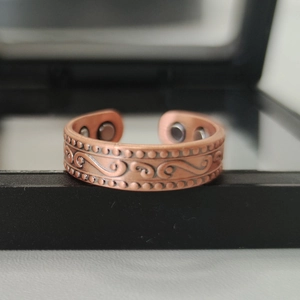 Macro detail of red copper magnetic ring with vintage swirls on black jewelry box