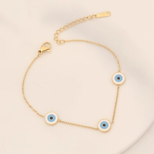 Macro detail of gold-plated evil eye bracelet with colorful enamel charms and lobster clasp