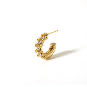 Detail of 18K gold plated C-shaped earring with sparkling cubic zirconia on white background