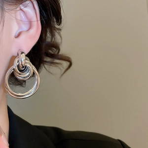 Gros plan de boucles d'oreilles nœuds argentées multicouches au fini poli brillant