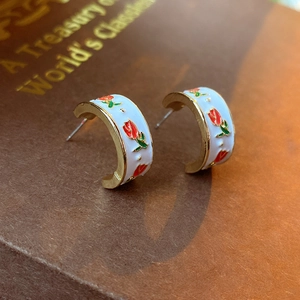 Détail macro de boucles d'oreilles tulipes dorées sur fond de livre vintage