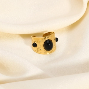 Detailed close-up of wide gold textured ring with three black gemstones on silk