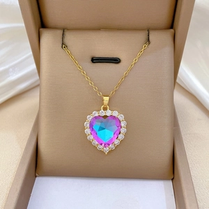 Macro view of golden heart pendant with purple-blue gradient stone and pavé zircons