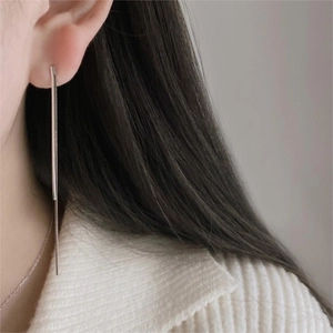 Minimalist long silver snake chain earring worn by a model in a close-up detail shot