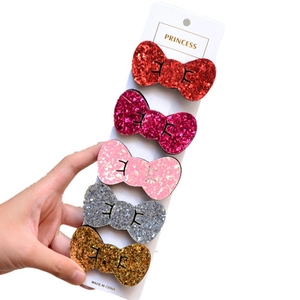 Close-up of five colorful glitter bow hair clips for girls on a display card