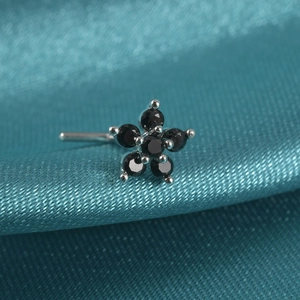 Macro detail of silver flower nose stud with black cubic zirconia on teal satin fabric