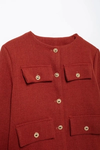 Vue détaillée d'une veste en tweed rouge foncé avec des boutons dorés en relief
