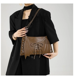 Sac à épaule marron pour femme avec design d'ailes, rivets métalliques et laçage.