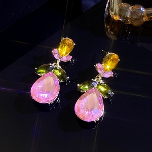 Vue macro de boucles d'oreilles en zircon coloré avec pierres roses et vertes sur miroir