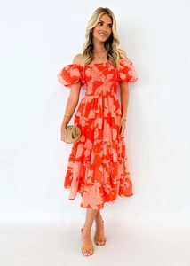 Détail d'une robe maxi à fleurs corail, épaules dénudées et jupon à plusieurs niveaux