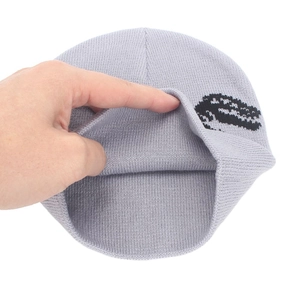 Detail view of the grey knitted beanie showing the double-layer structure and dinosaur pattern